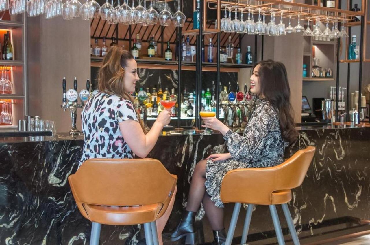 Clayton Hotel Manchester City Centre Kültér fotó Two women talking while having drinks at a bar